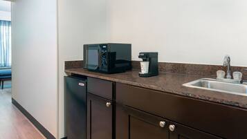 A kitchen with a microwave, coffee maker, and sink.