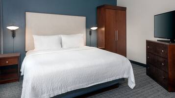 A hotel room with a bed, a wooden wardrobe, a television, and two wall-mounted lamps.