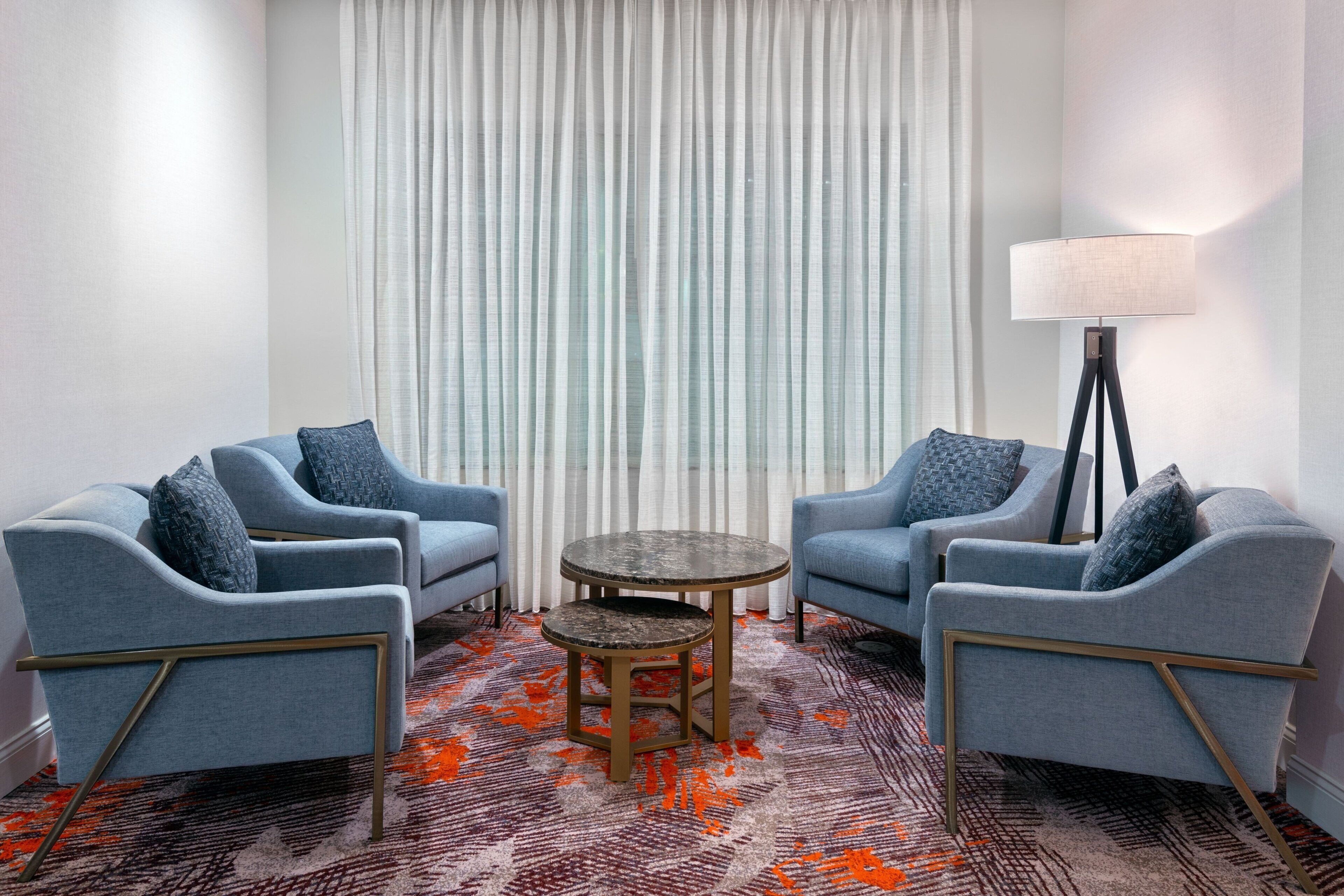 A room with two blue armchairs, a small round table, and a floor lamp.