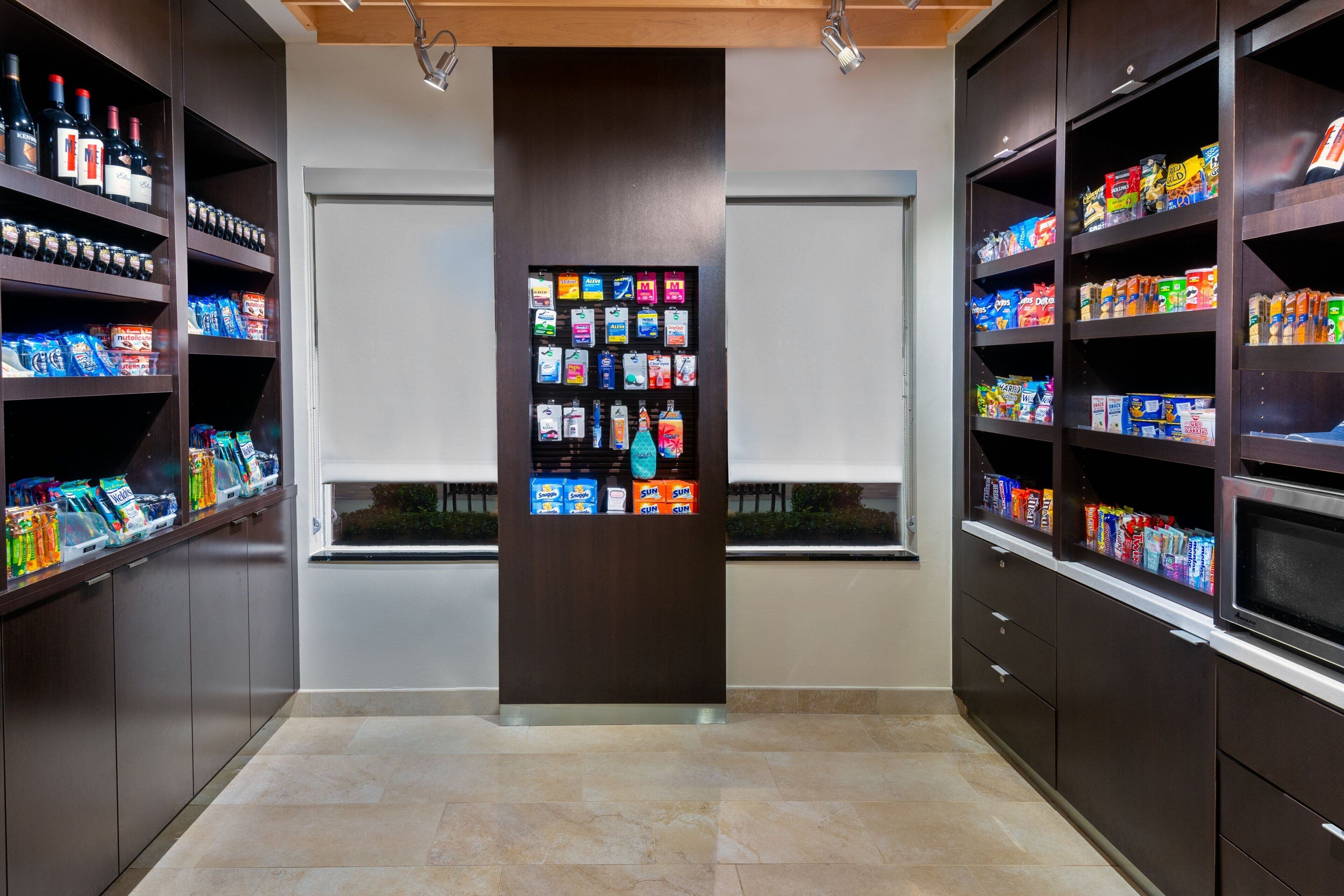 A modern retail space with shelves stocked with snacks and beverages, a central display case, and a clean, tiled floor.