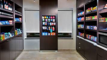 A modern retail space with shelves stocked with snacks and beverages, a central display case, and a clean, tiled floor.
