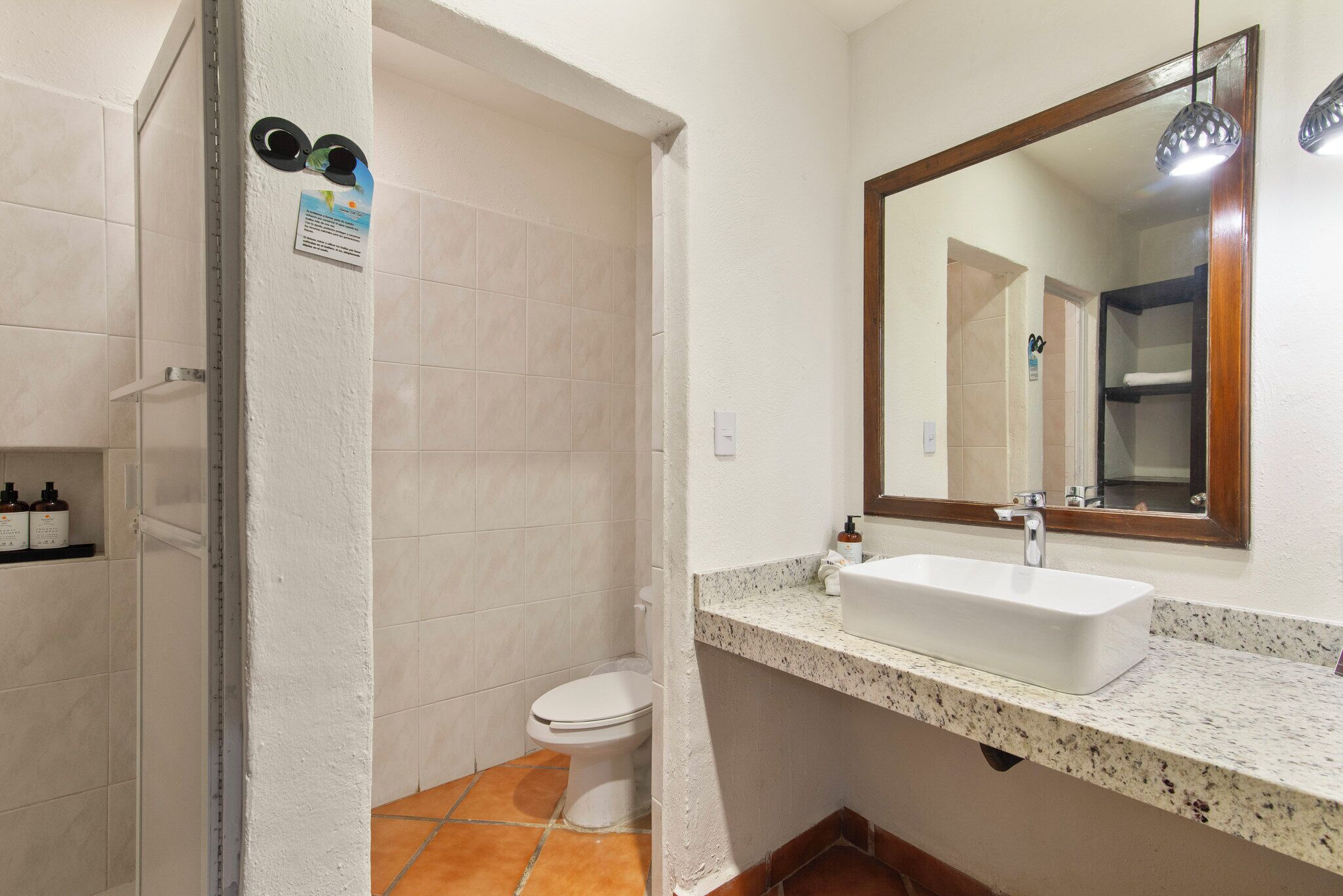 Une salle de bain avec un lavabo blanc, un miroir et un espace douche.