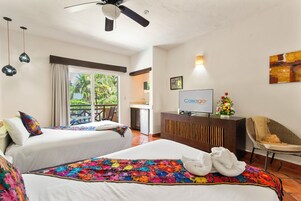A hotel room with two beds, a ceiling fan, a TV, and a desk with a flower vase.