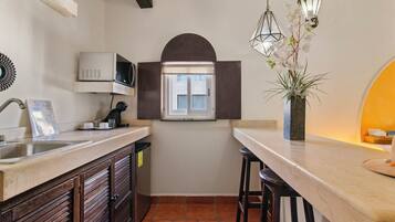 A compact kitchen with a microwave, sink, and a small window.