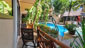 Un espace aménagé au bord de la piscine, avec une rambarde en bois, des chaises et des plantes en pot.