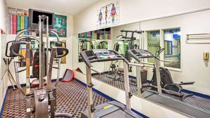 Un gimnasio con equipamiento cardiovascular, una cinta de correr y un espejo grande.