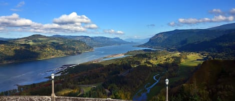 A scenic view of a river valley with a bridge and lamp posts.