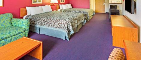 A hotel room with two beds, a sofa, a wooden table, and a television.