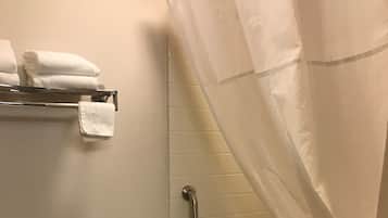 A bathroom with a toilet, a shower with a curtain, a grab bar, and a towel rack with towels.