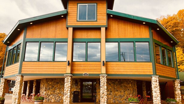 A two-story building with a stone facade, large windows, and a covered entrance area with outdoor seating. - Econo Lodge Lakeview (Marquette)