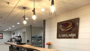 A reception desk with a wooden finish, overhead lighting, and a sign reading "EcoLodge". - Econo Lodge Lakeview (Marquette)