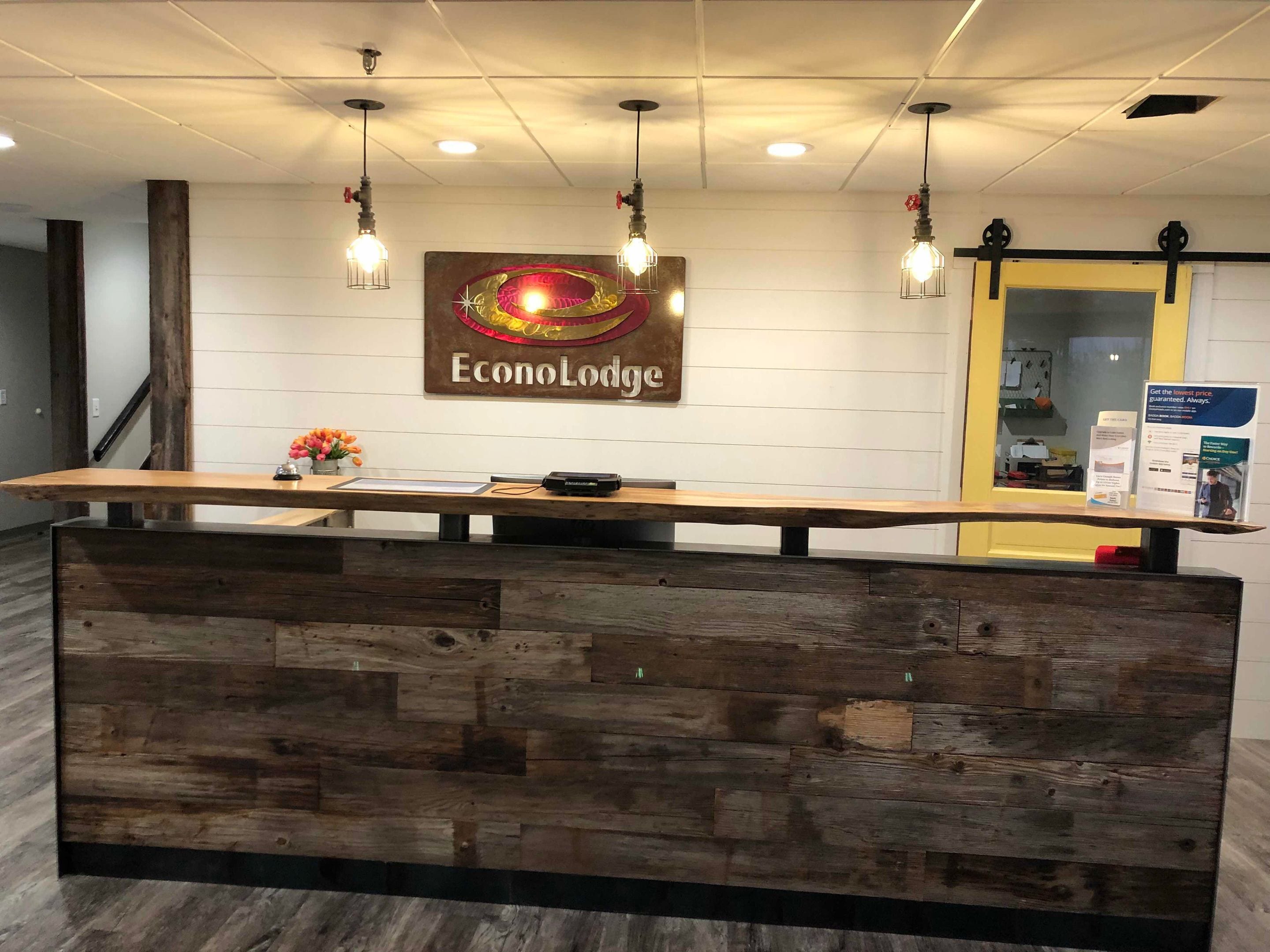 A reception desk with a wooden finish, a sign reading "EconoLodge," and three hanging light fixtures.