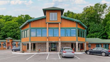 Situated in a parking lot, this two-story building features a unique architectural style with a prominent green roof and large windows.