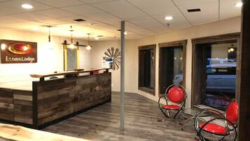 A reception area with a wooden reception desk, two red chairs, and a clock on the wall.
