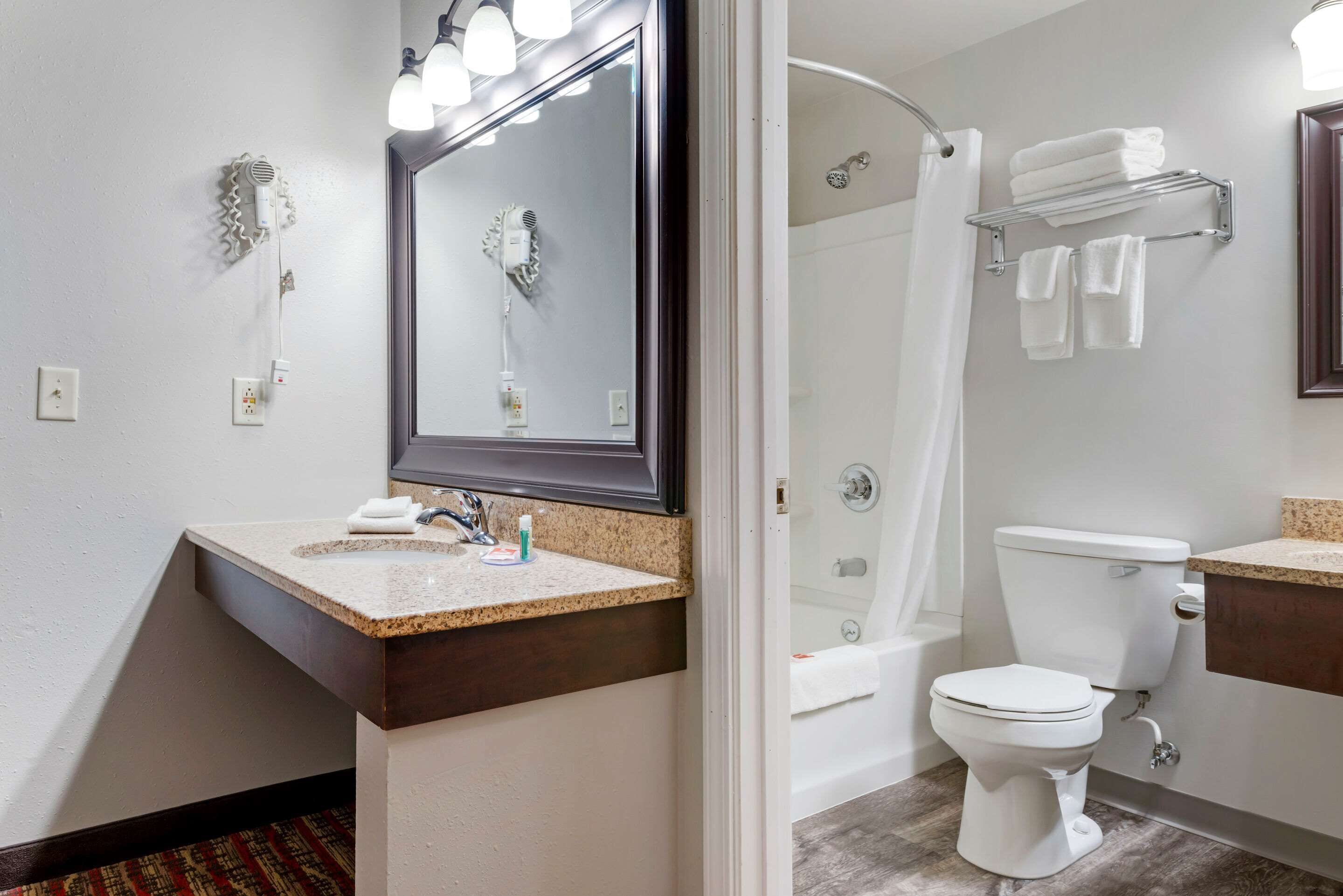 Ein Badezimmer mit Waschbecken, Spiegel, Handtuchhalter, Toilette und Dusche.