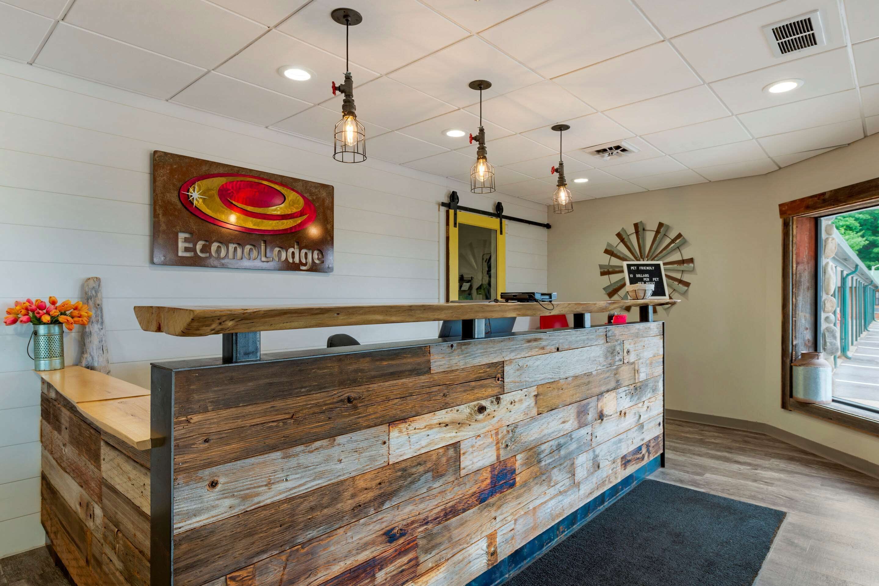 A reception desk with a wooden finish, a sign above it, and pendant lighting.