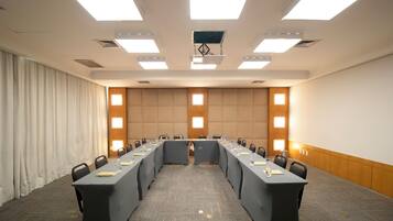 Uma sala de conferências com uma mesa comprida, cadeiras e uma tela de projeção.