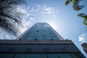 Un immeuble imposant, doté d’une façade en verre, se dressant sous un ciel dégagé.