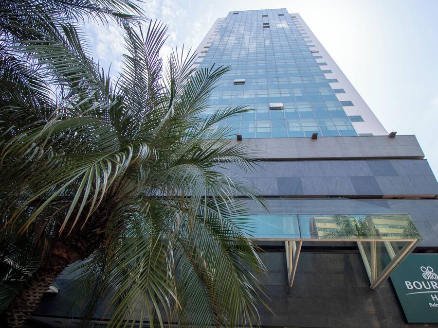 A tall hotel building with a glass facade and a sign for the Bourbon Hotel.