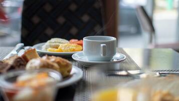 A breakfast setting with a cup, plate of pastries, and a chair.