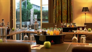 Une chambre d’hôtel dotée d’un coin repas comprenant un bar avec diverses bouteilles et verres, une table avec des pommes et un stylo rouge, et offrant une vue sur la verdure environnante.