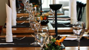 Une table à manger dressée avec des verres à vin, des assiettes et des couverts, donnant sur un paysage verdoyant.