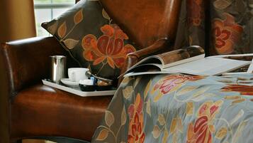 Un sillón de cuero con un cojín estampado con motivos florales y una bandeja con una taza y un platillo.