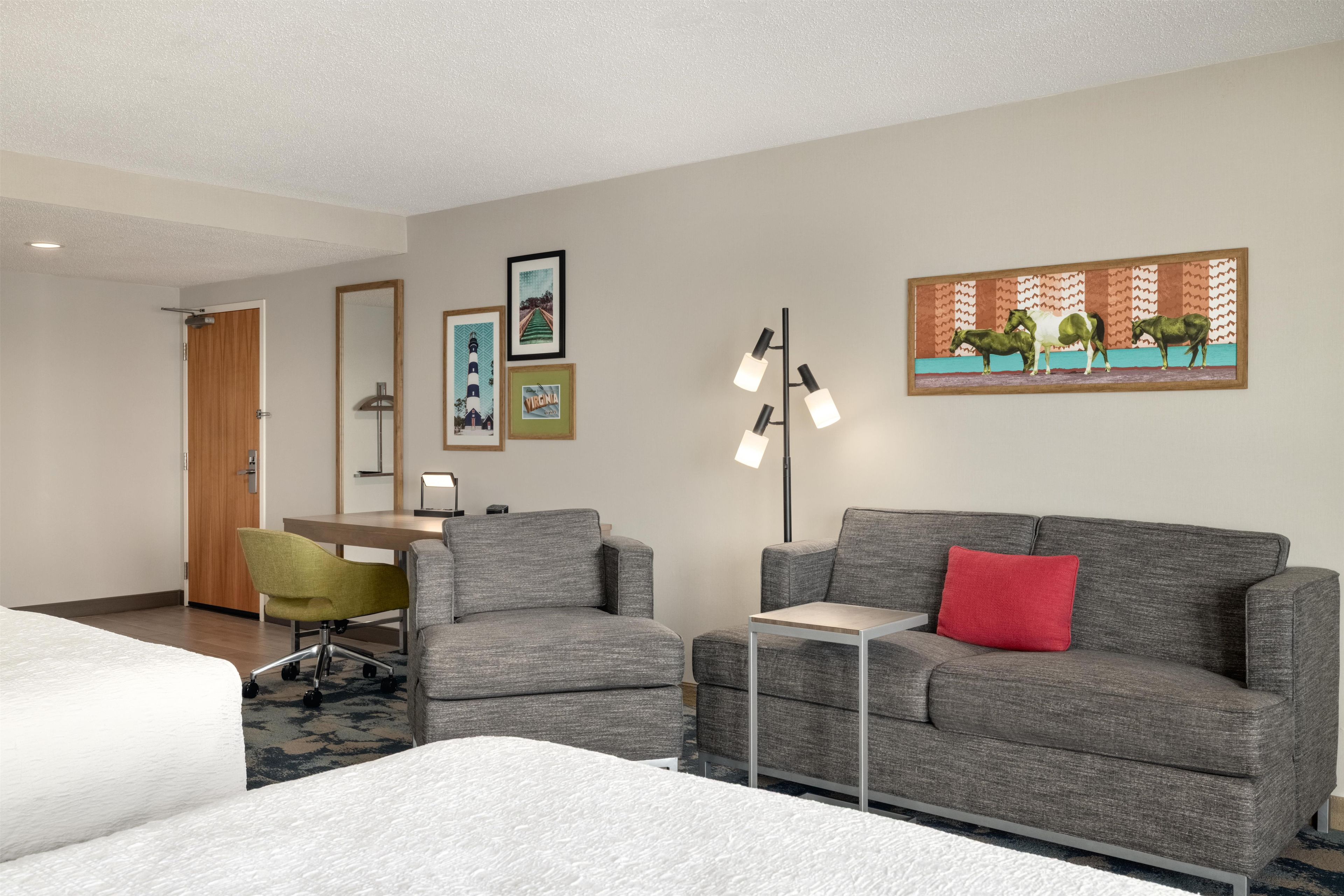 A hotel room with a bed, two armchairs, a sofa, a desk, and a floor lamp.