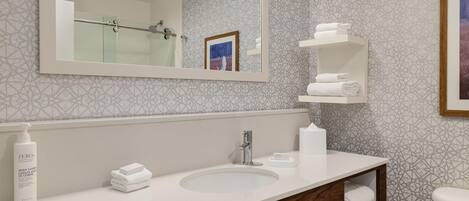 A modern bathroom with a large mirror, a sink, a toilet, and a shower.