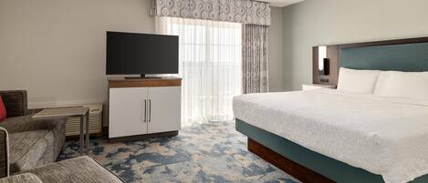 A hotel room with a bed, a television on a stand, a desk, and a chair.