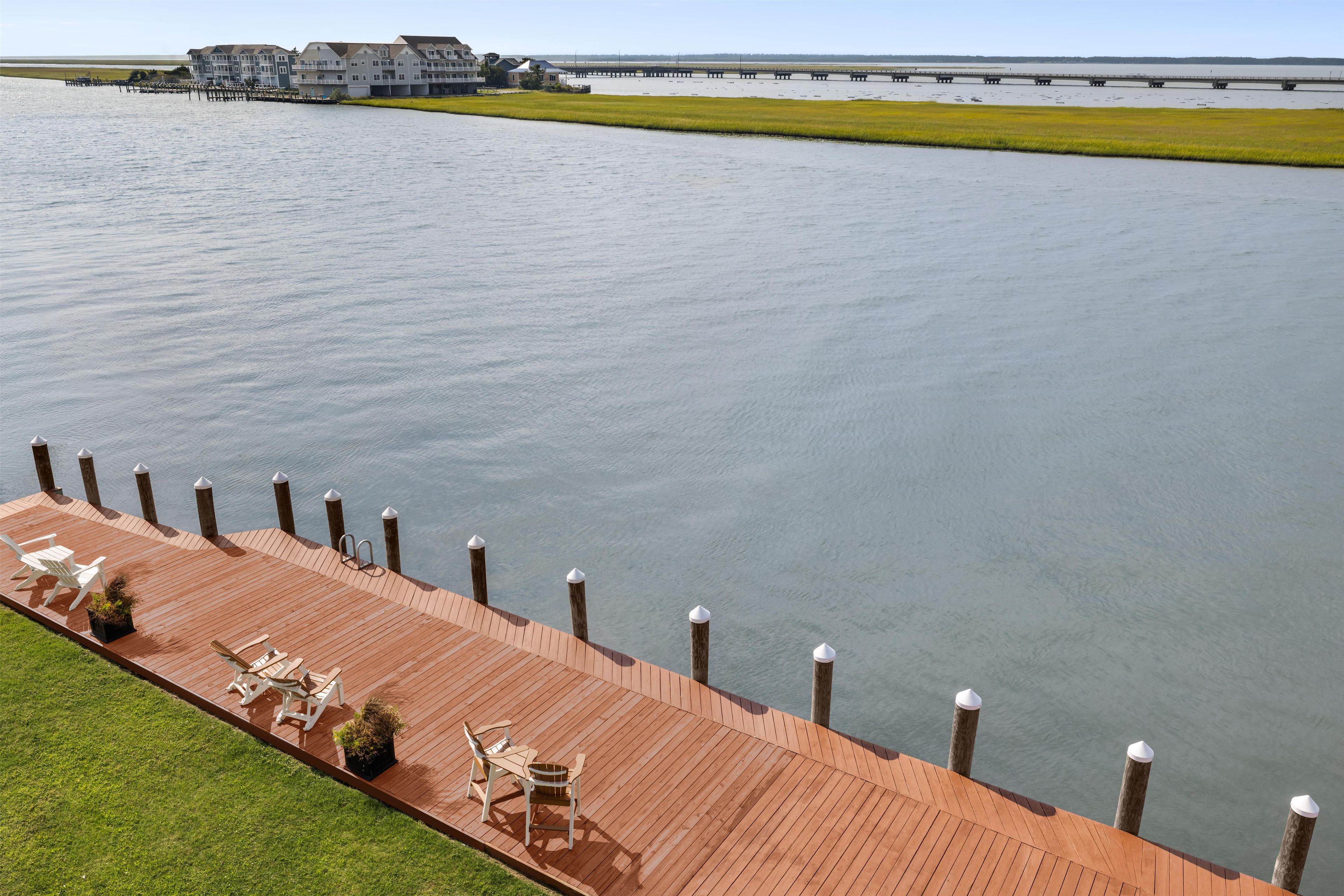 A waterfront property with a wooden deck, outdoor seating, and a view of the water.