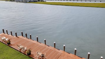 A waterfront property with a wooden deck, outdoor seating, and a view of the water.