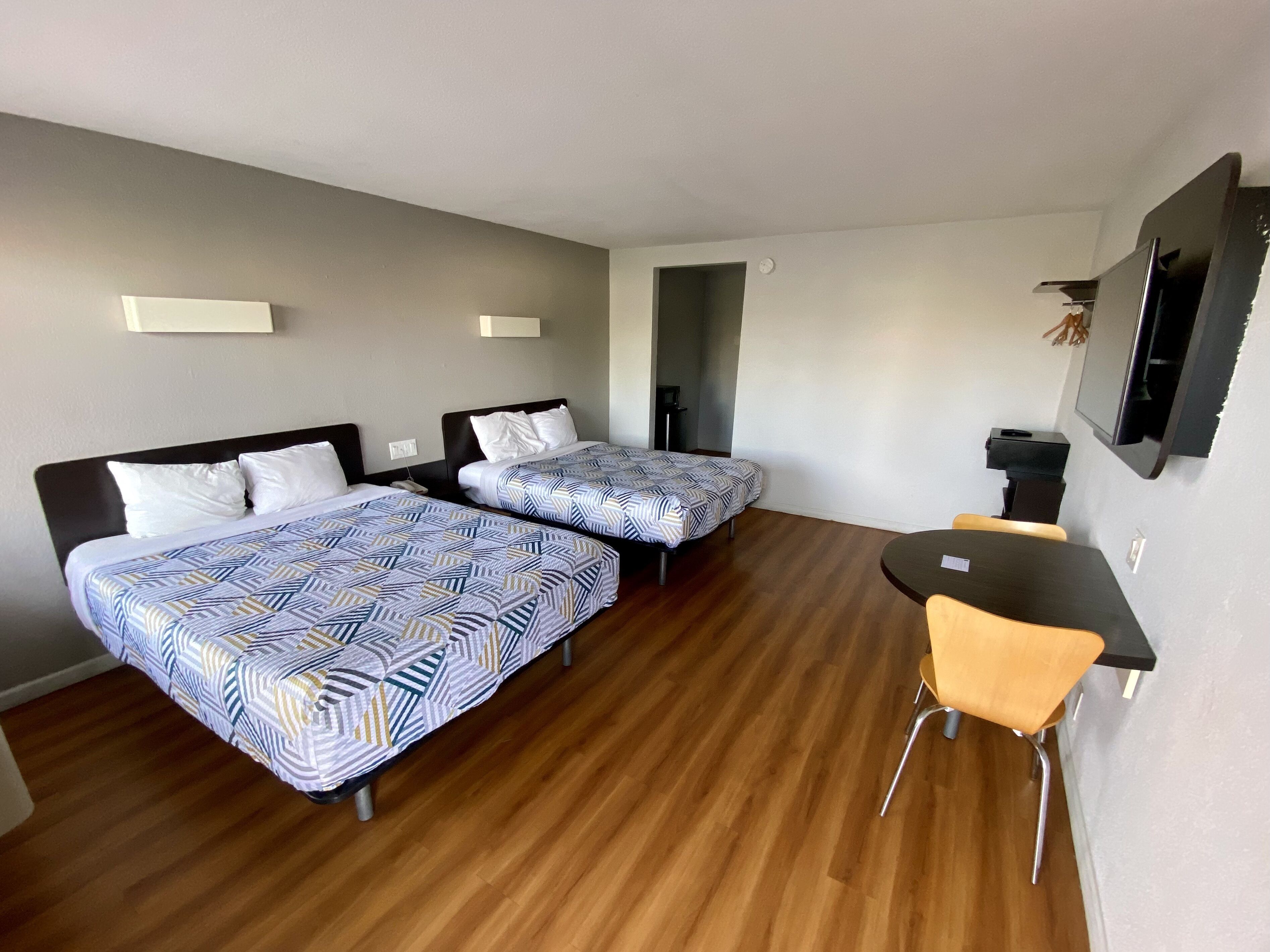 Habitación de hotel con dos camas, un escritorio y una silla.