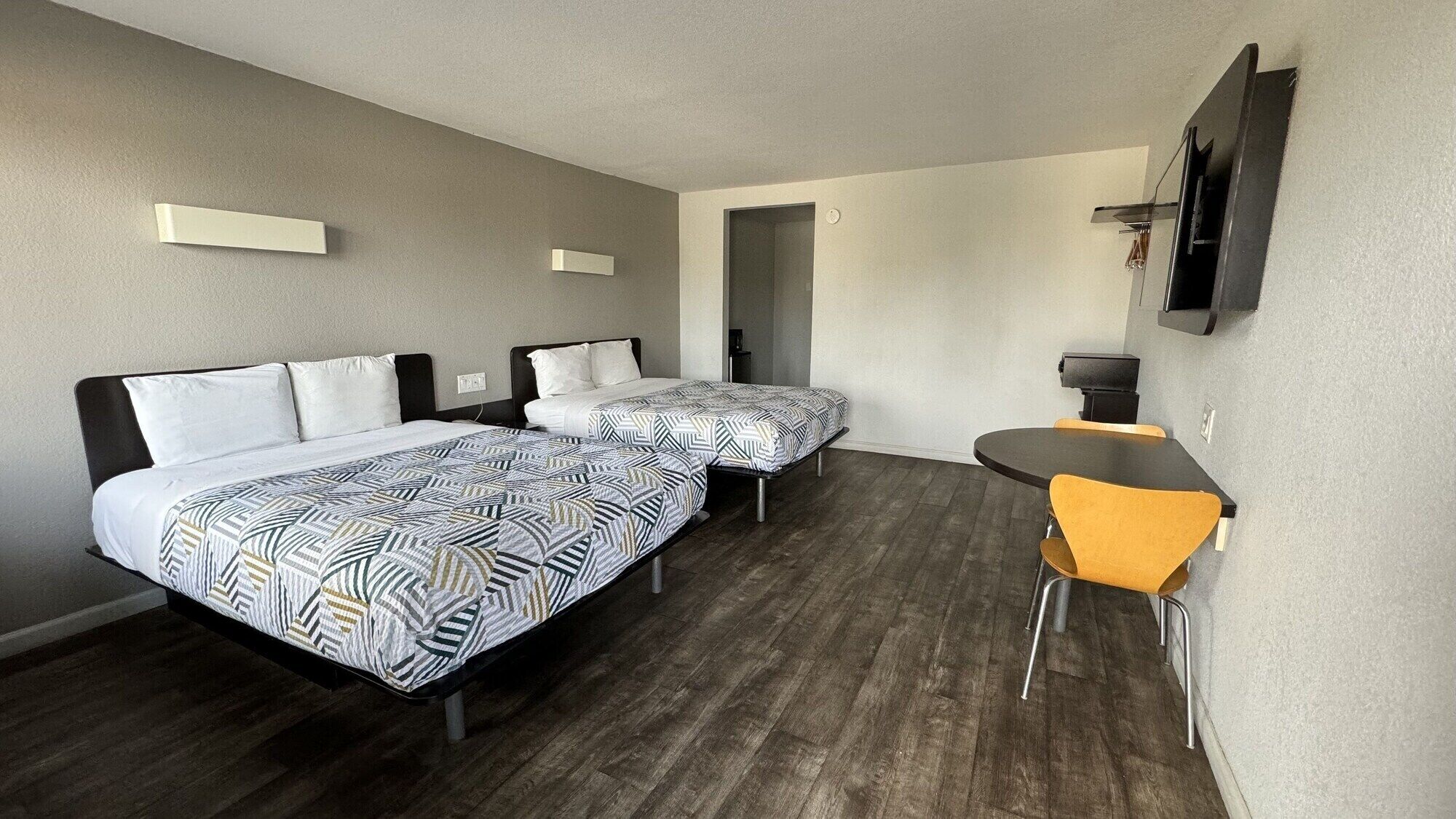 Une chambre d’hôtel avec deux lits, une petite table et une chaise.