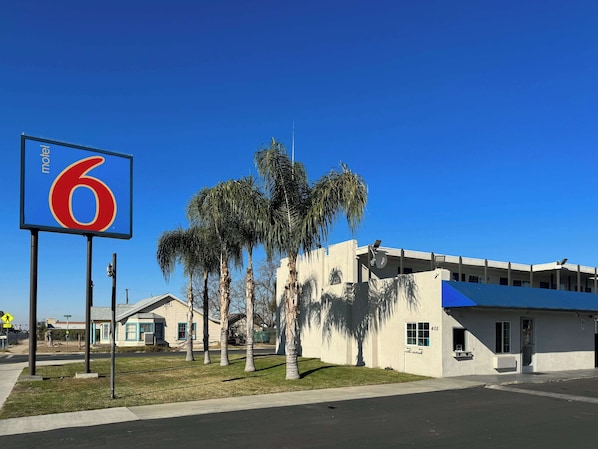 A motel with a large '6' sign, palm trees, and a building with a blue roof.