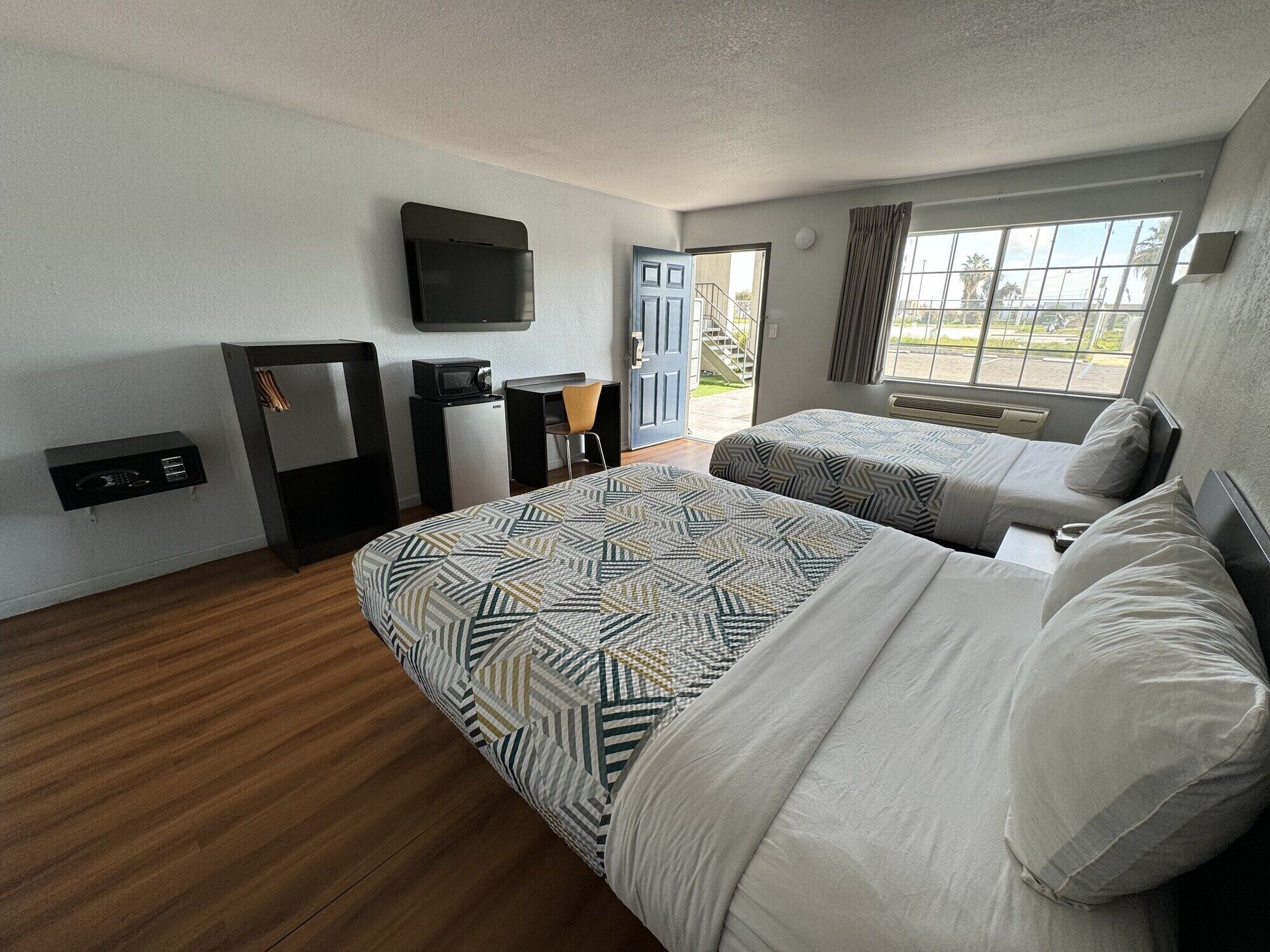 Una habitación de hotel con dos camas, un escritorio, un televisor y una ventana con vistas.