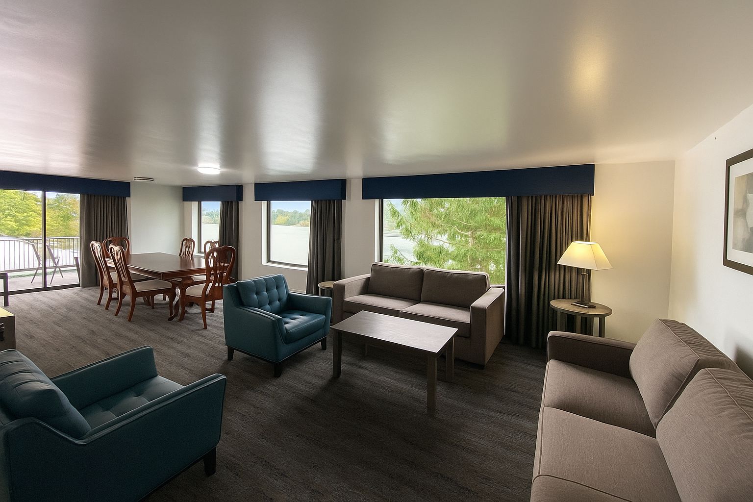 Quarto de hotel com uma mesa de jantar, dois sofás, uma mesa de centro e um abajur.