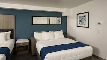 Une chambre d’hôtel comprenant un lit, une table de chevet, une chaise, un bureau et un miroir fixé au mur.