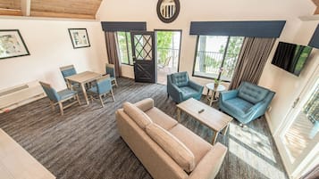 Amplia sala de estar con sofá, sillas, una mesa y un balcón con puerta.