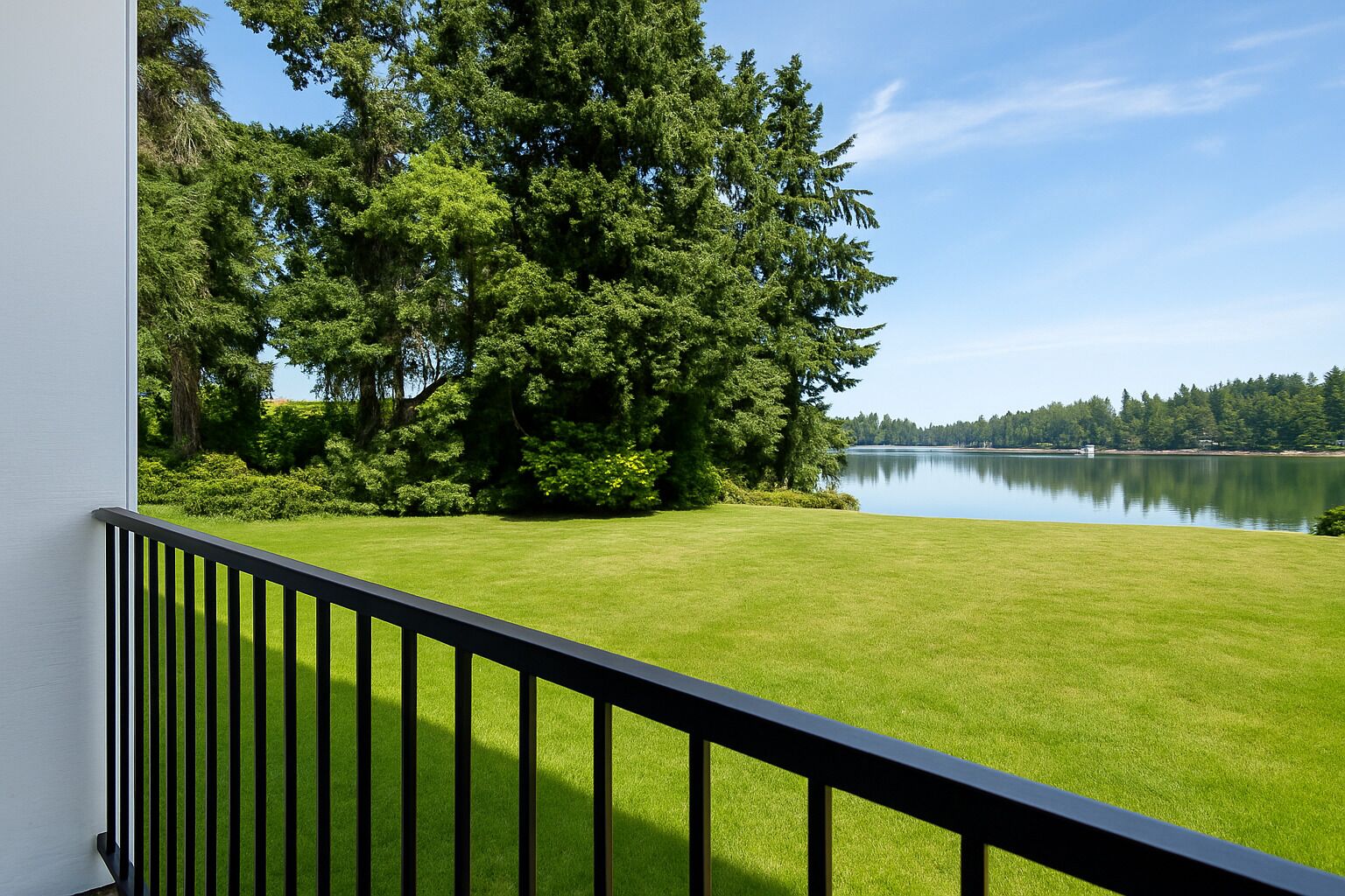 Een balkon met uitzicht op een verzorgd gazon en een meer.