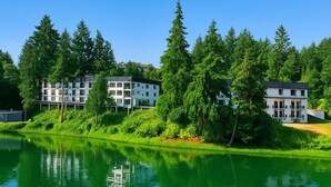 Un hotel frente al lago con arquitectura moderna, que cuenta con varios balcones y un reflejo en el agua.