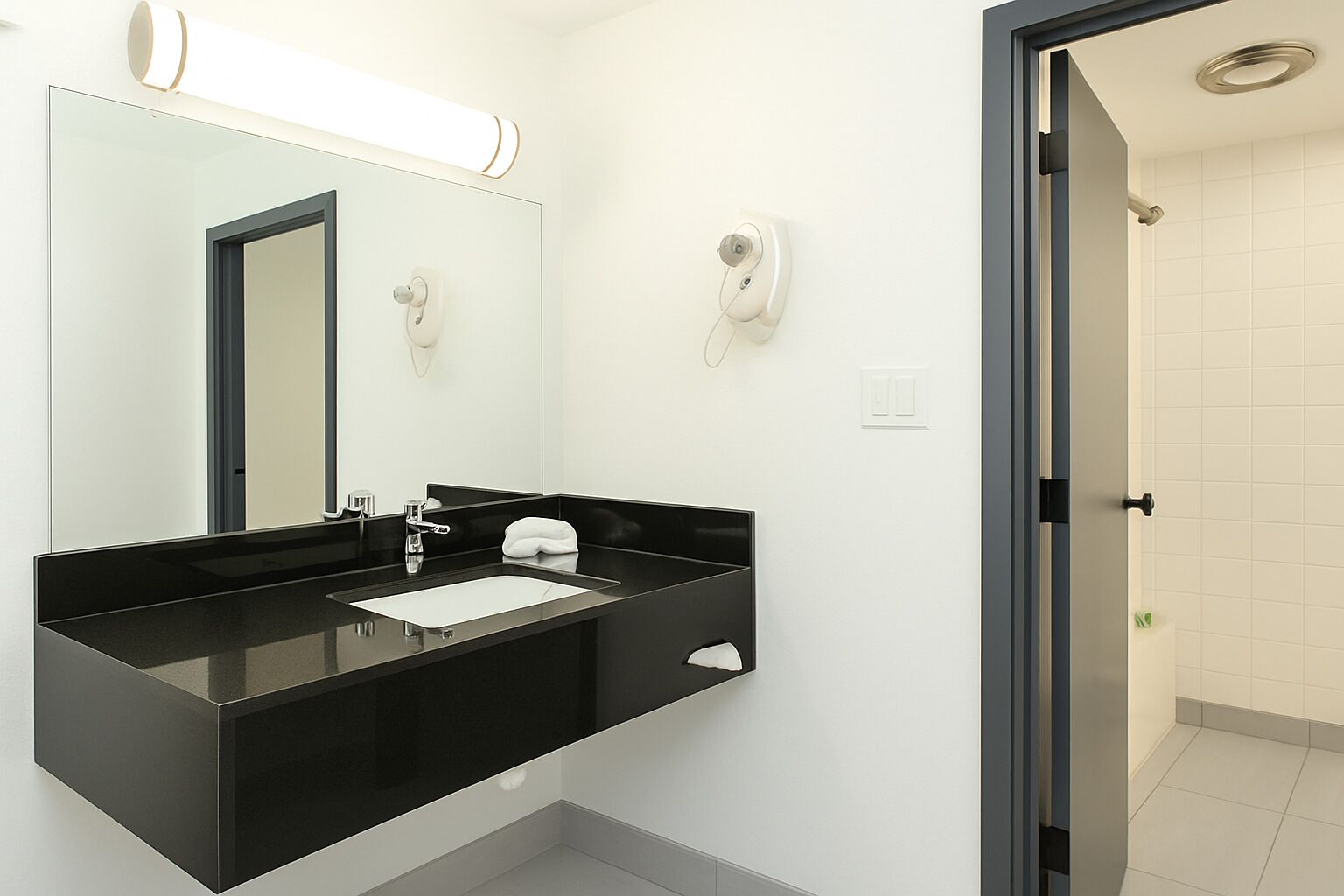 A modern bathroom with a black sink, a mirror, and a toilet.