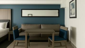 A modern room with a sofa, two chairs, a table, and a bed.