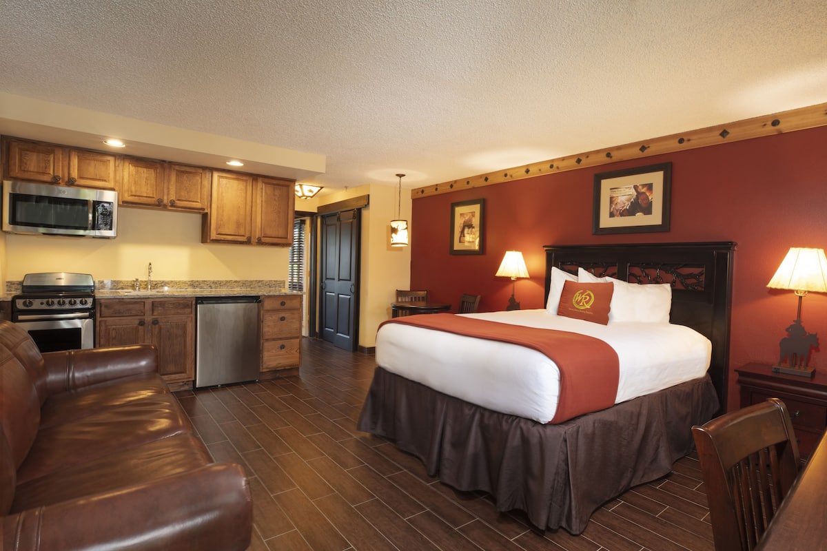 Une chambre d’hôtel comprenant un lit, un bureau, une chaise, une kitchenette et une salle de bain.