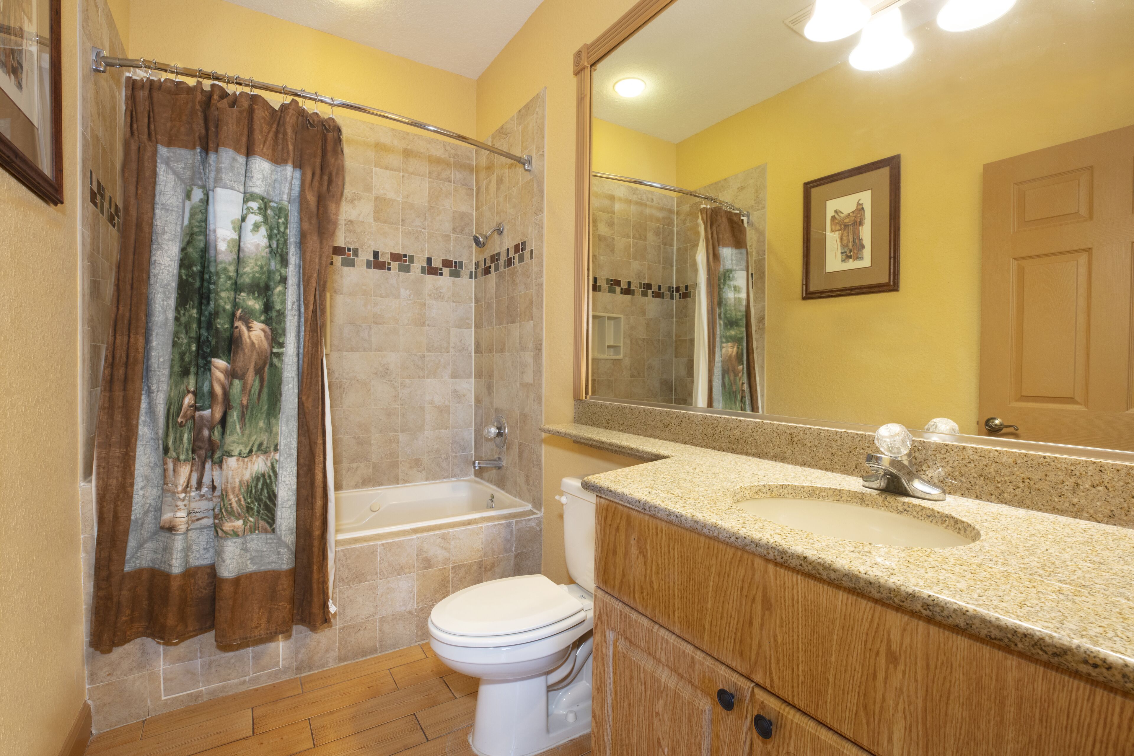 A bathroom with a shower, toilet, sink, and a large mirror.