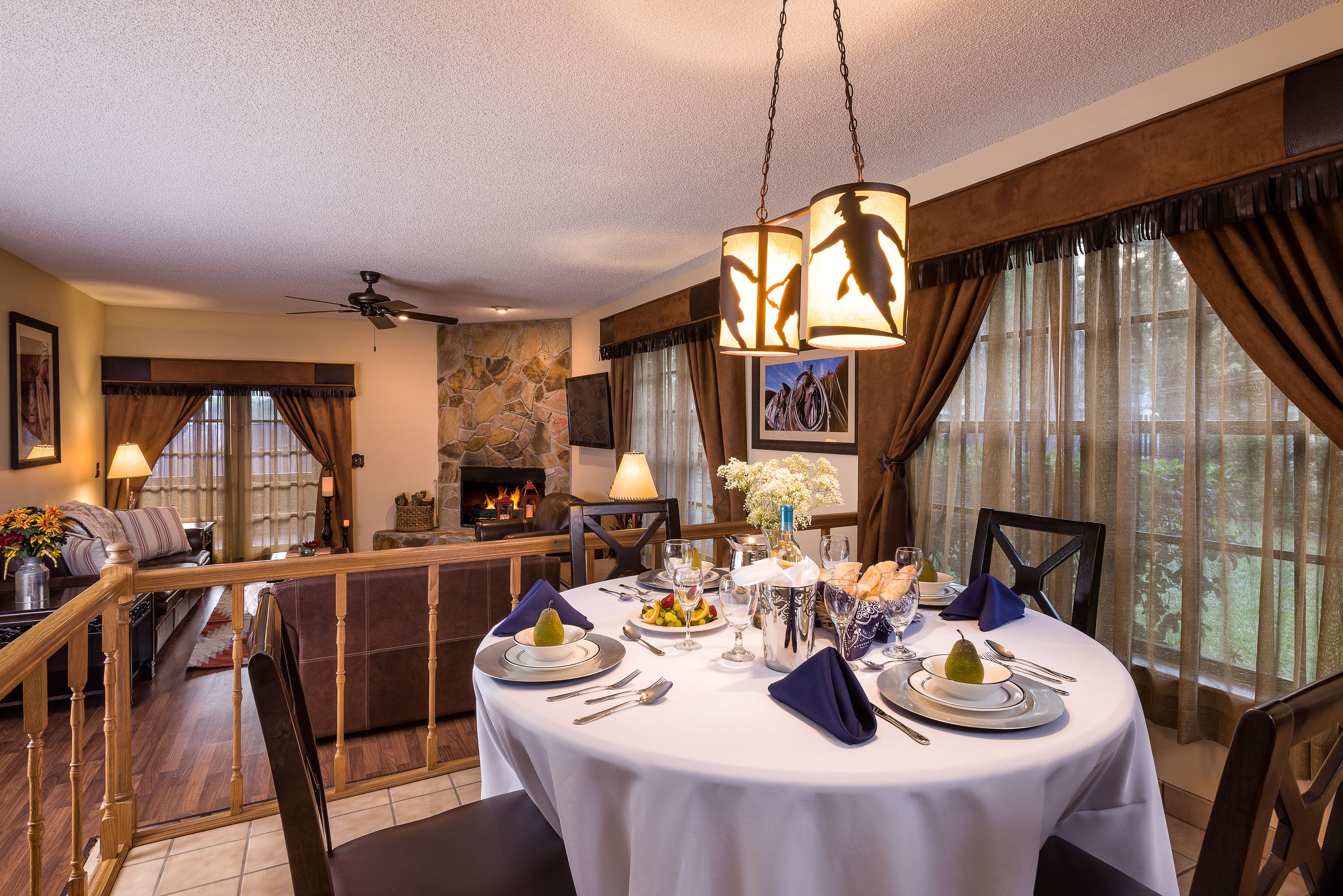 Un coin repas avec une table ronde dressée pour quatre personnes, une cheminée et une vue sur l’extérieur.