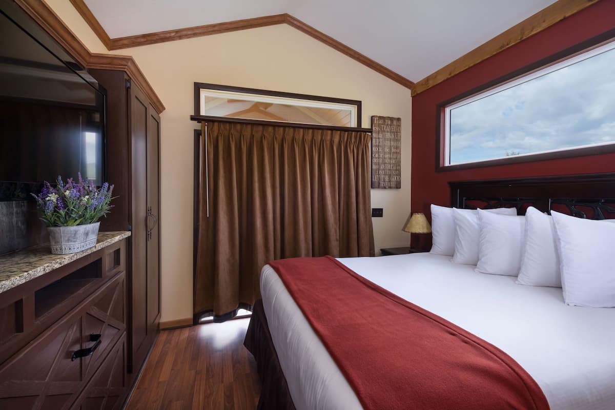 A hotel room with a bed, a television, a window, and a wall with a motivational quote.