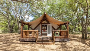 A rustic wooden structure with a covered entrance, a wooden deck, and a circular emblem on the front. - Westgate River Ranch Resort & Rodeo (River Ranch)