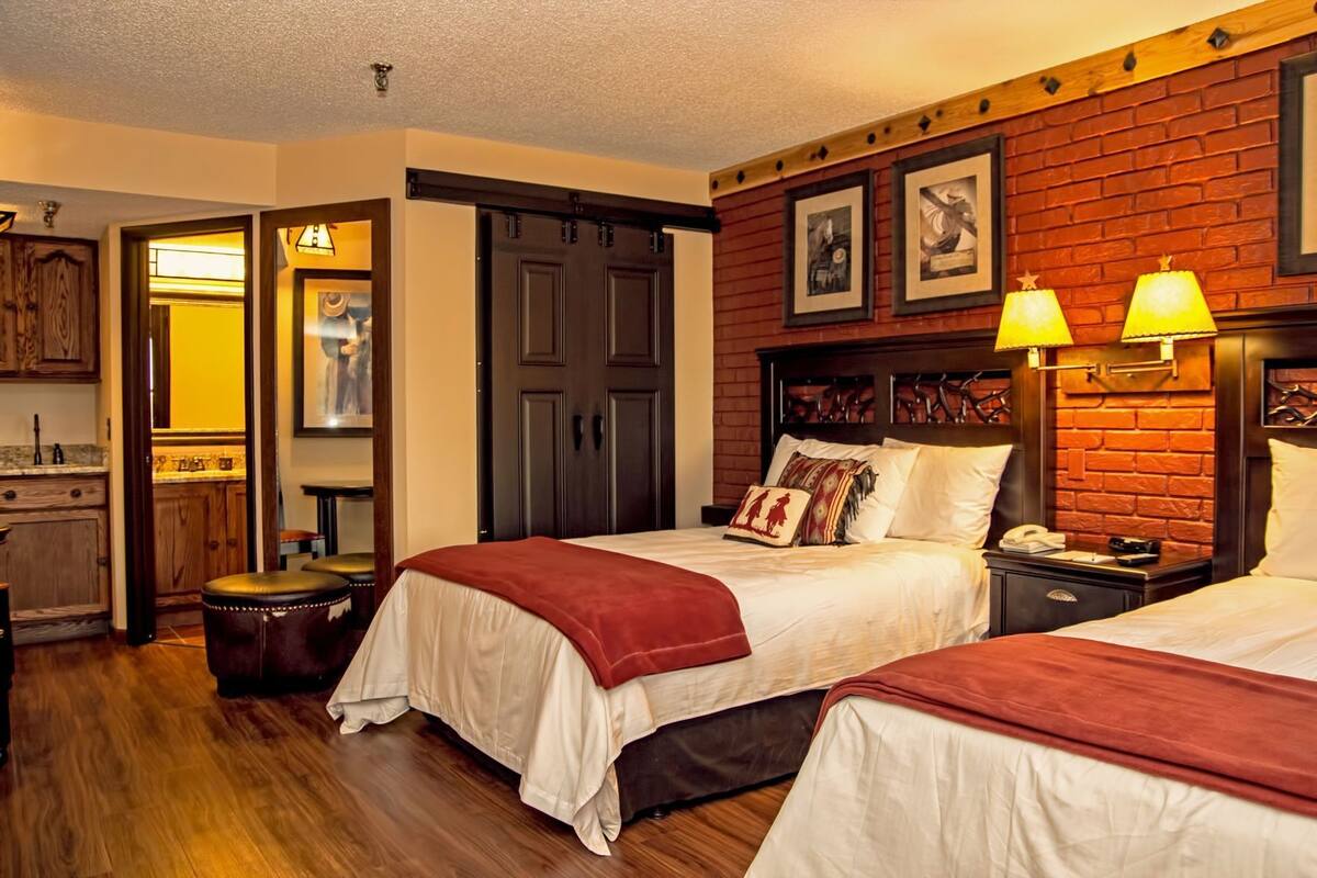 Une chambre d’hôtel avec deux lits, un mur décoratif en briques et un plancher en bois.