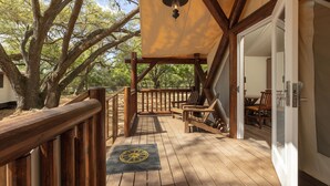 A wooden deck with a pergola, outdoor seating, and a door leading to an interior space.